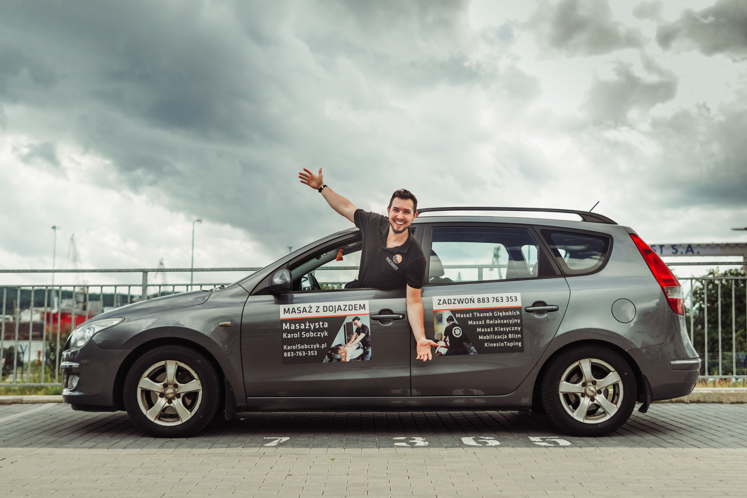 samochód z reklamą mobilnego masażu stojący na parkingu